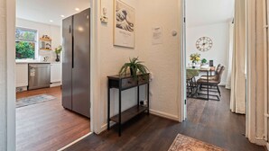 Eine moderne Küche mit Kühlschrank, ein Essbereich mit Tisch und Stühlen sowie ein Flur mit einer Konsole und einer Uhr.