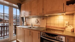 A kitchen with wooden cabinets, a stainless steel sink, a stove, and a view through a glass door. - Alpine Apartment with Parking and Balcony (Hol)
