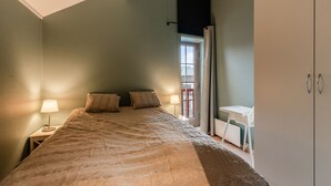 A bedroom with a bed, two bedside lamps, a window with curtains, and a white wardrobe. - Alpine Apartment with Parking and Balcony (Hol)