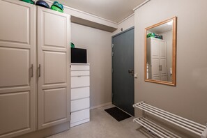 Un couloir avec une armoire blanche, une porte sombre, un radiateur et un miroir accroché au mur.