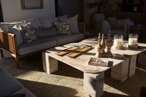 Ein Wohnzimmer mit einem Marmortisch, einer Couch und einem kleinen Tisch mit Kerzen und Büchern.