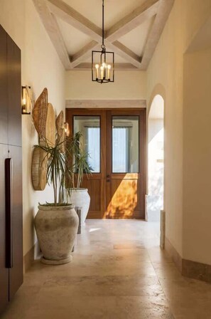 A hallway with a wooden door, a large potted plant, and a hanging light fixture. - Heated Pool & Spa Villa 5BR for 12, Fire Pit (San José del Cabo)