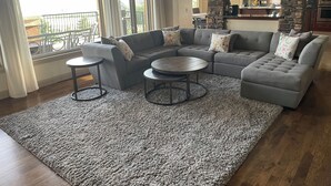 A living room with a sectional sofa, two round coffee tables, and a view of the kitchen and balcony. - Peaceful Monument Retreat (San José del Cabo)