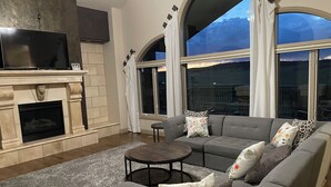 A living room with a fireplace, a sofa set, a coffee table, and large windows with curtains. - Peaceful Monument Retreat (San José del Cabo)
