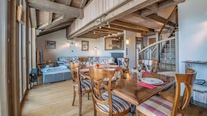 A dining area with a wooden table, chairs, and a staircase leading to an upper level. - La Forêt du Praz (Courchevel)