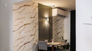 A dining area with a marble-patterned wall, a wooden dining table, and chairs. - Beach & Rainforest House with Private Pool (Rio Grande)