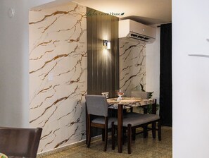 A dining area with a marble-patterned wall, a wooden dining table, and chairs. - Beach & Rainforest House with Private Pool (Rio Grande)