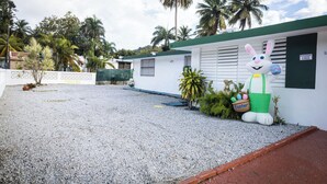 A building with a white exterior, a green roof, and a large bunny statue holding an Easter basket. - Beach & Rainforest House with Private Pool (Rio Grande)