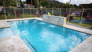 A rectangular swimming pool with a stone border and a small waterfall feature. - Beach & Rainforest House with Private Pool (Rio Grande)