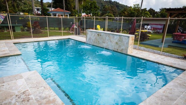 A rectangular swimming pool with a stone border and a small waterfall feature.
