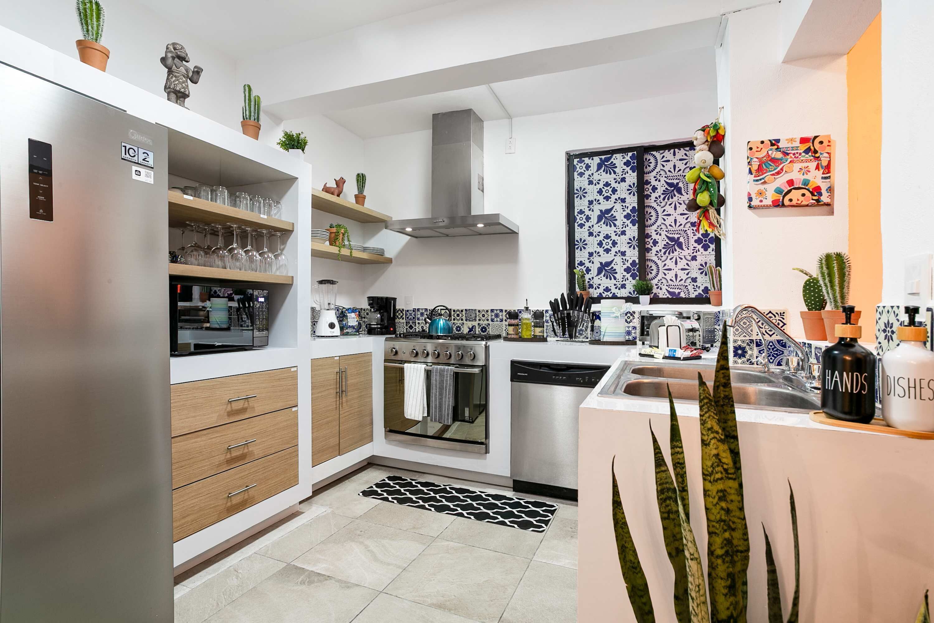 A modern kitchen with a stainless steel refrigerator, wooden cabinets, a built-in oven, and a coffee machine.