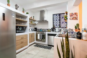 Eine moderne Küche mit Edelstahl-Kühlschrank, Holzschränken, Backofen und einer Kaffeemaschine.
