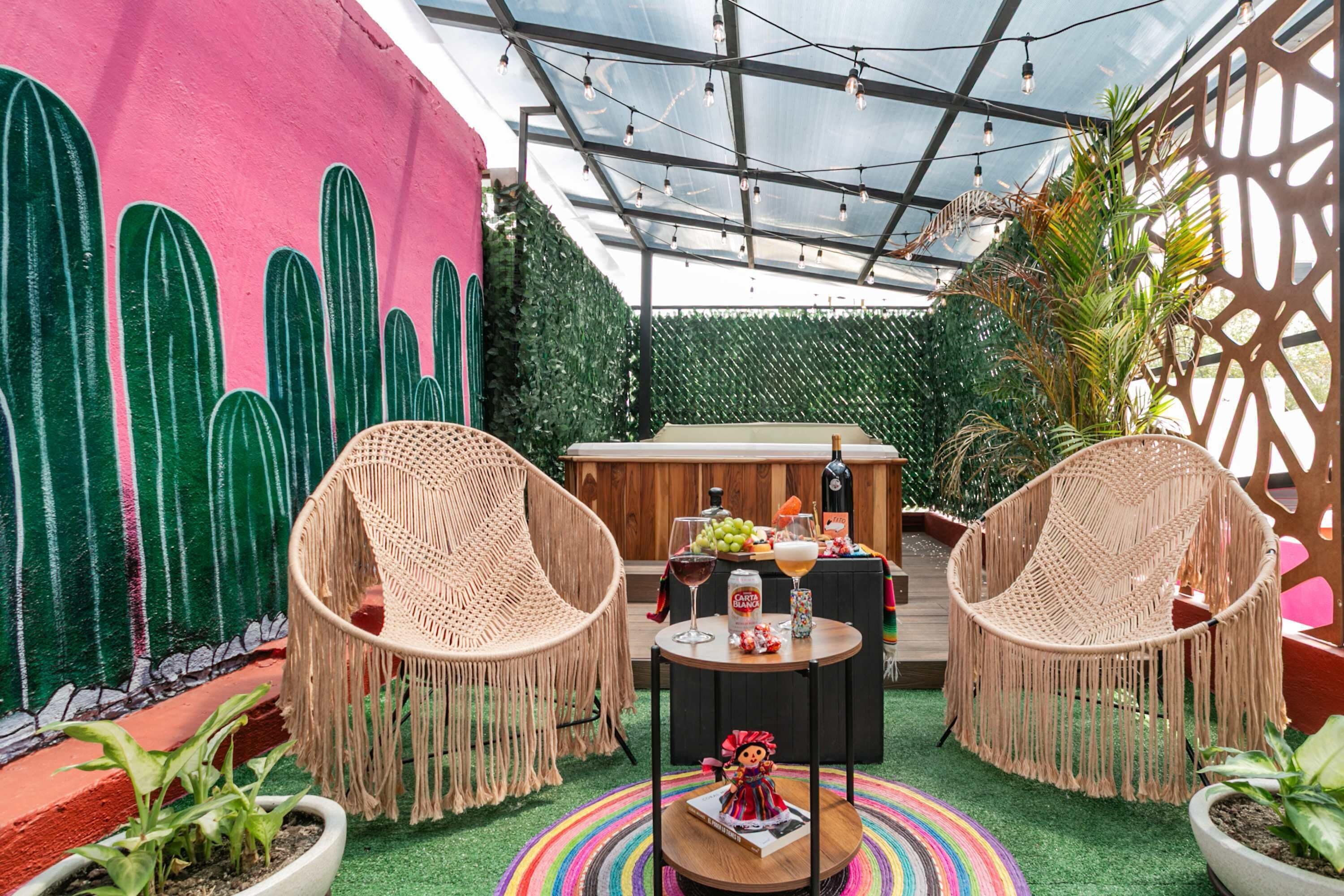 A cozy outdoor seating area with wicker chairs, a small round table, and a colorful striped rug.