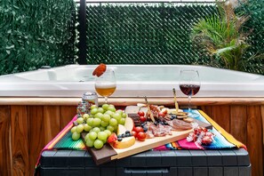 A hot tub with a wooden table in front, holding a cheese board, grapes, and a can of beer. - Condesa 7-suite villa · hot tub & pool table (Mexico City)