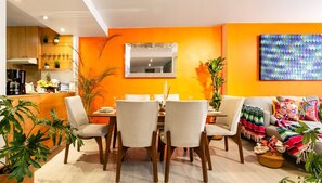A dining area with a table and chairs, a kitchen in the background, and a colorful wall art piece. - Quiet-Street Condesa 3BR, 2 Kings, Balconies & AC (Mexico City)