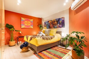 A modern bedroom with a bed, a large painting, and two potted plants. - Quiet-Street Condesa 3BR, 2 Kings, Balconies & AC (Mexico City)