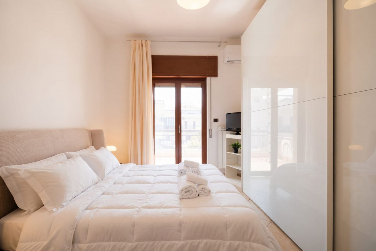 Una camera da letto con un letto, una televisione, un armadio e una finestra con tende.