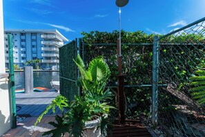 Zona de piscina al terrat amb una tanca metàl·lica, plantes en testos i una vista d'un edifici alt al fons.