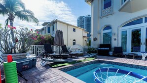 Uma área de piscina com espreguiçadeiras, mesa de bilhar e um bar tiki.
