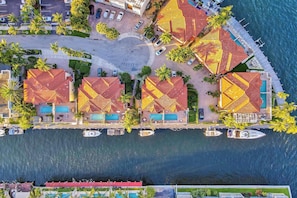 Luchtbeeld van een kusthotel met meerdere gebouwen, een zwembad en een steiger met boten.