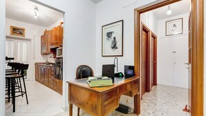 A room with a wooden desk, a chair, a laptop, and a framed picture on the wall.