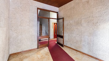 Een gang met een rood tapijt, een houten plafond en een gestructureerde wand.