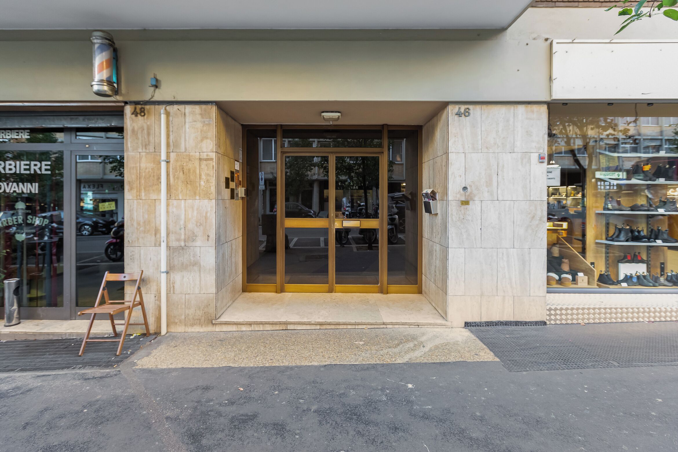 Une devanture de magasin avec une grande porte vitrée, un banc en bois à l’extérieur et un présentoir à chaussures à l’intérieur.