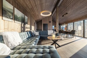 A modern interior with a sectional sofa, a round coffee table, and a dining area with chairs.