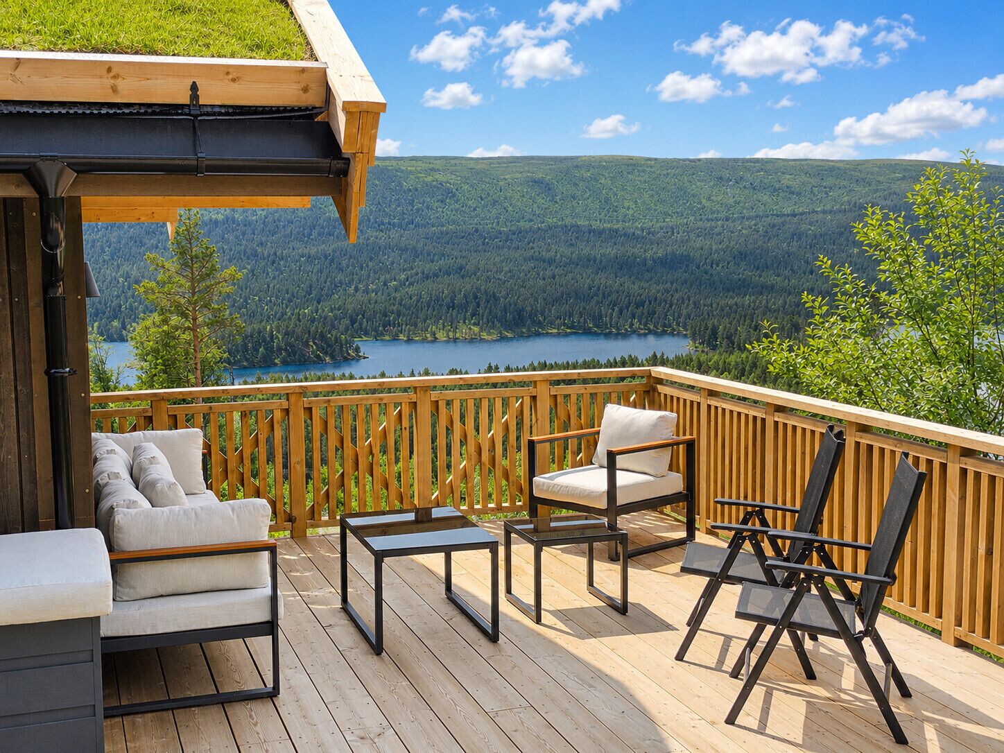 Eine Holzterrasse mit Gartenmöbeln, einem Pergola und einem schönen Blick auf einen See und einen Wald.