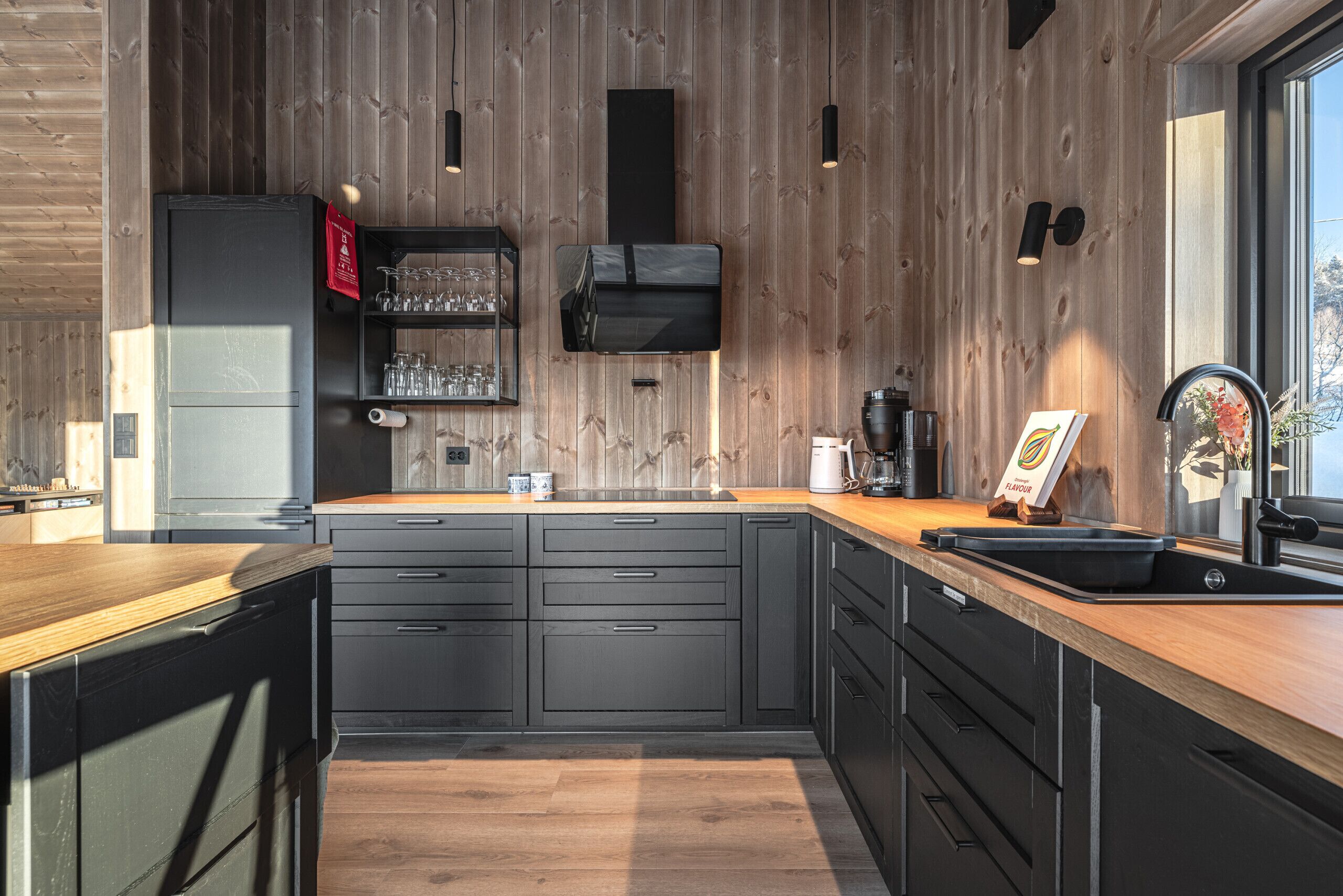 Une cuisine moderne avec des murs en bois, un four encastré et une grande fenêtre.