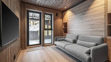 Un interior moderno con techo de madera, un sofá gris y un ventanal grande.