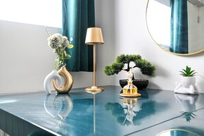 Ein modernes Zimmer mit einer spiegelnden Oberfläche, einer Lampe, einem Bonsai-Baum und Dekorationselementen.