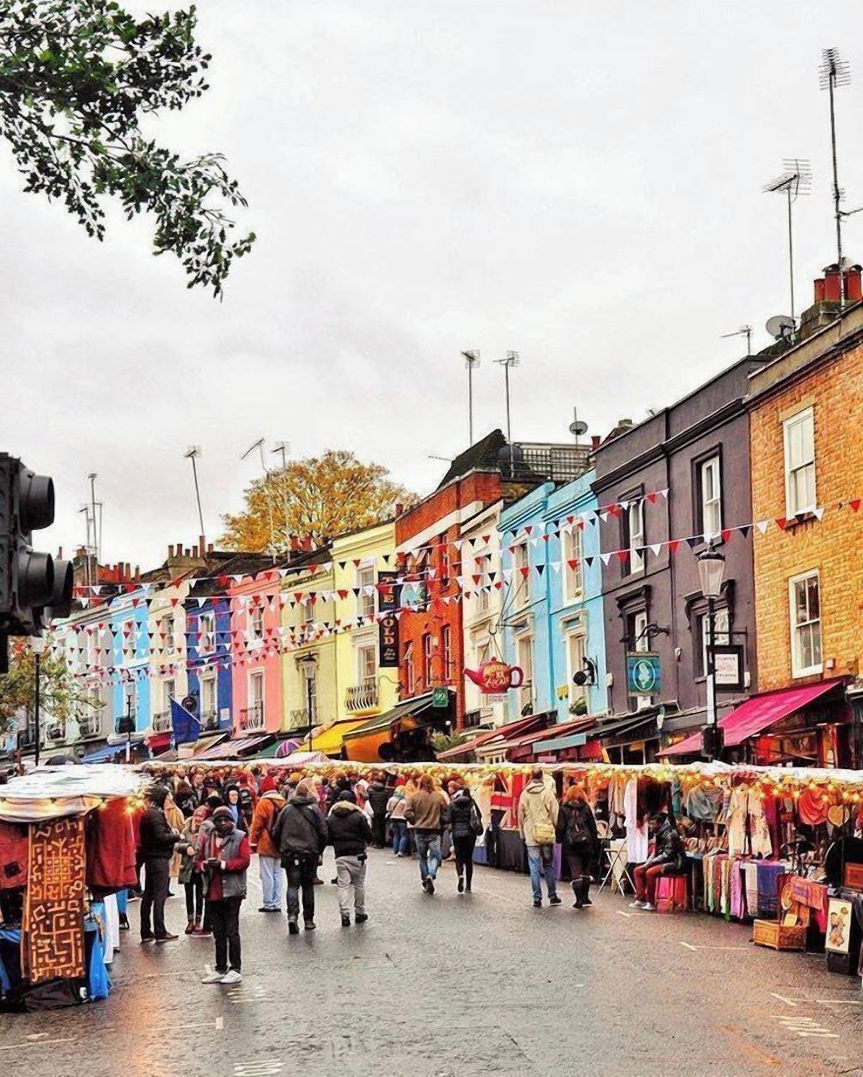 A busy street market with people shopping and vendors selling goods.