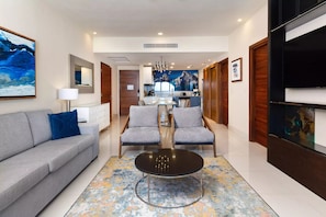 A modern living room with a sofa, two armchairs, a coffee table, and a kitchen in the background.