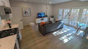Un salon moderne avec un canapé, un téléviseur et un coin repas doté d’une table en verre.
