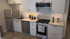 Une cuisine moderne dotée d’appareils électroménagers en acier inoxydable, d’un revêtement mural en carreaux et d’un plancher en bois.