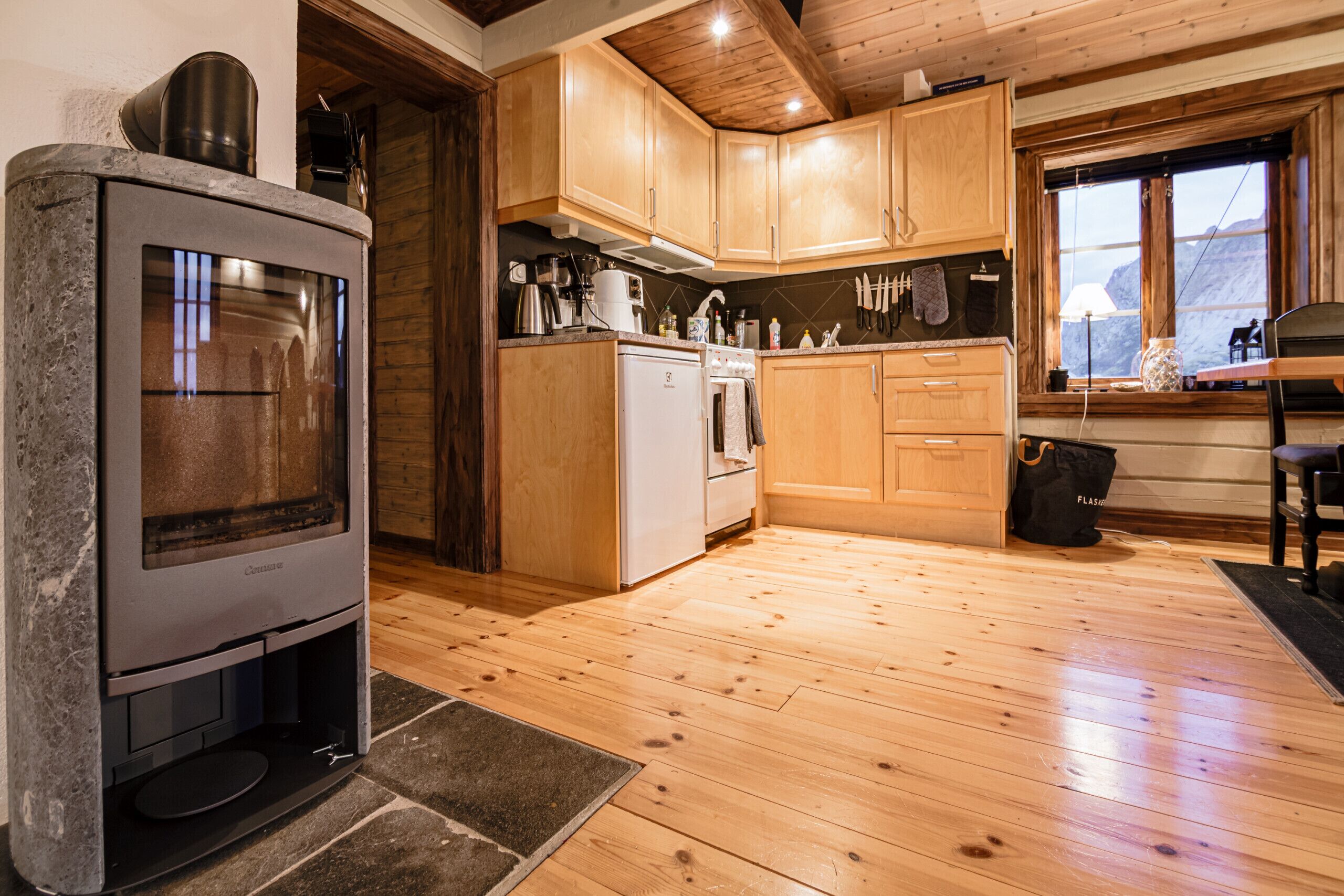 A kitchen with wooden cabinets, a stove, and a window.
