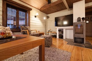 A cozy living room with a wooden dining table, a sofa, a fireplace, and a television.