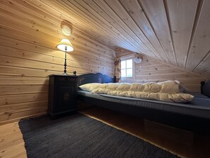 Una cama individual en una habitación con paredes de madera y techo inclinado.