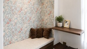A cozy seating area with a patterned wall, a hanging light fixture, and a small table with a plant and picture frame. - Central Paris Apartment near Opéra & Galeries Lafayette (Paris)