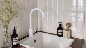 A modern bathroom with a white sink, wooden countertop, and a vase with flowers. - Central Paris Apartment near Opéra & Galeries Lafayette (Paris)