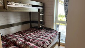 A bunk bed with a wooden headboard, a plaid bedspread, and a window with curtains. - TexasToppen, cabin in Hafjell with sauna (Øyer)