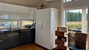 A modern kitchen with white cabinets, a built-in dishwasher, and a large window offering a view of the outdoors. - TexasToppen, cabin in Hafjell with sauna (Øyer)