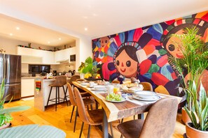 Een moderne keuken met witte kastjes, een roestvrijstalen koelkast en een ontbijtruimte met een houten tafel.