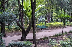 Ein Park mit einem gepflasterten Weg, Bänken und verschiedenen Bäumen und Sträuchern.