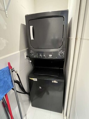 Eine kompakte, dunkel gefärbte Waschmaschine mit Bedienknöpfen und einem kleinen Staukasten.