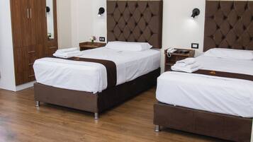 Een hotelkamer met twee bedden, een kledingkast, een nachtkastje en kunst aan de muur.