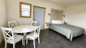 Une pièce avec un lit, une table et des chaises, et une fenêtre.