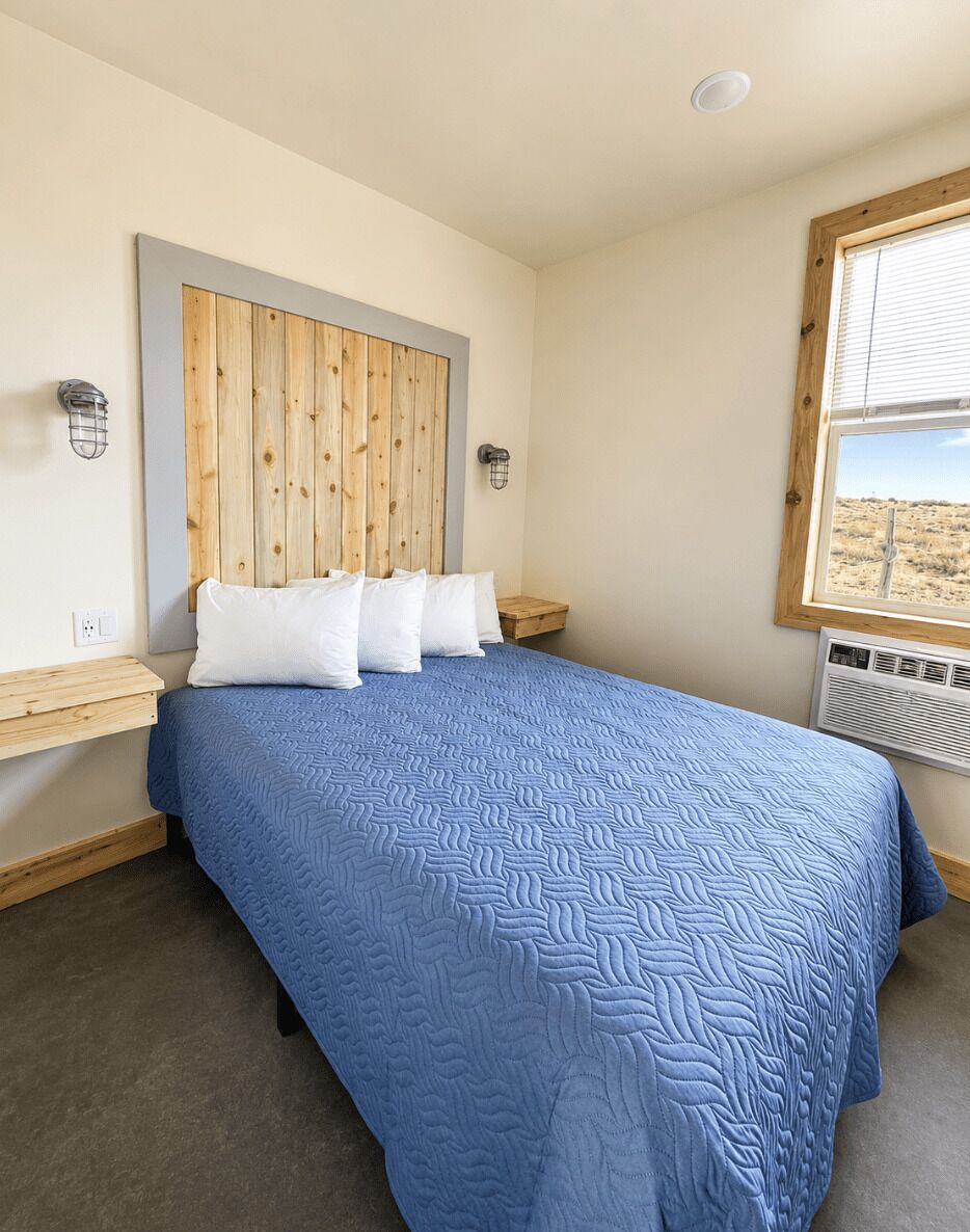 A bedroom with a bed, wooden headboard, bedside tables, and a window.