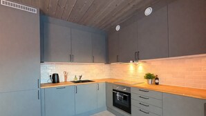 Una cocina moderna con armarios grises, encimera de madera, horno integrado y una pequeña planta en maceta.